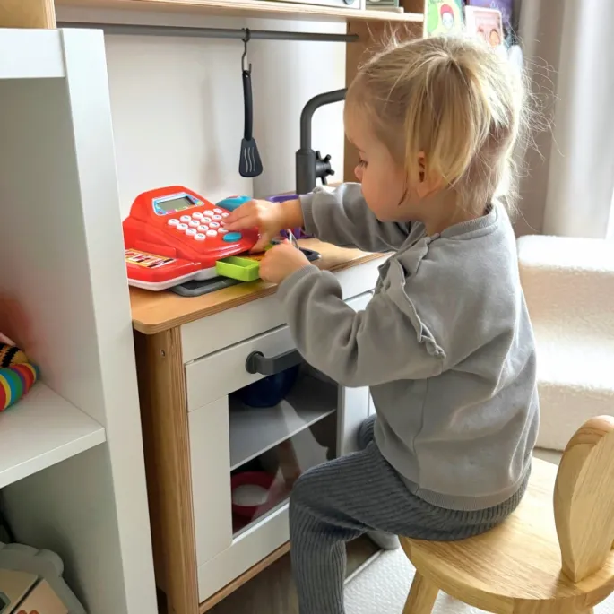 Dziecko bawi się w sklep z kasą i produktami spożywczymi