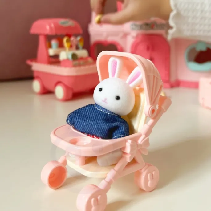 Maluch króliczka bawiący się w różowym wózeczku