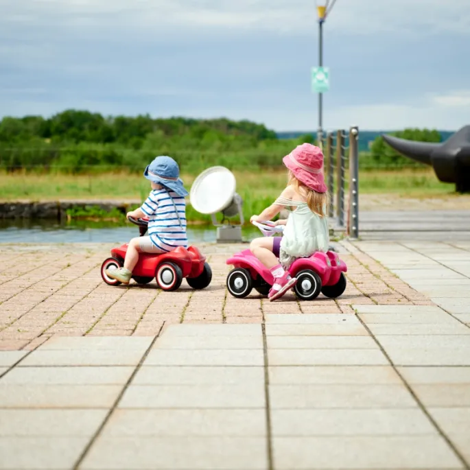Maluch bawi się jeździkiem BIG Bobby Car Neo Red na trawie.