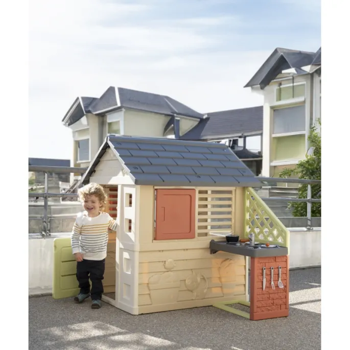 Dzieci bawią się w ogrodzie w domku Smoby