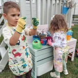 Dziecko używa konewki do podlewania roślin