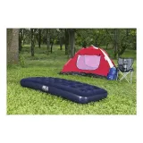 Materac dmuchany granatowy jednoosobowy ustawiony w plenerze obok namiotu