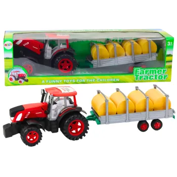 Duży czerwony traktor rolniczy z przyczepą i balami siana na białym tle