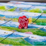 Rozłożona plansza gry z kartami i pionkami na stole