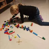 ręka dziecka ustawiająca kolorowy klocek podczas zabawy domino