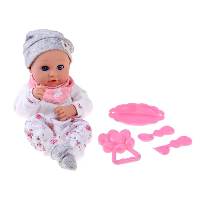 Lalka z czapeczką i różowym śliniaczkiem na tle akcesoriów