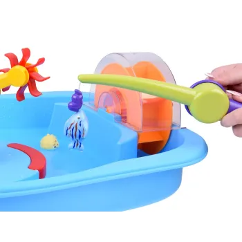 dziecko łowiące rybki plastikową wędką przy stoliku wodnym