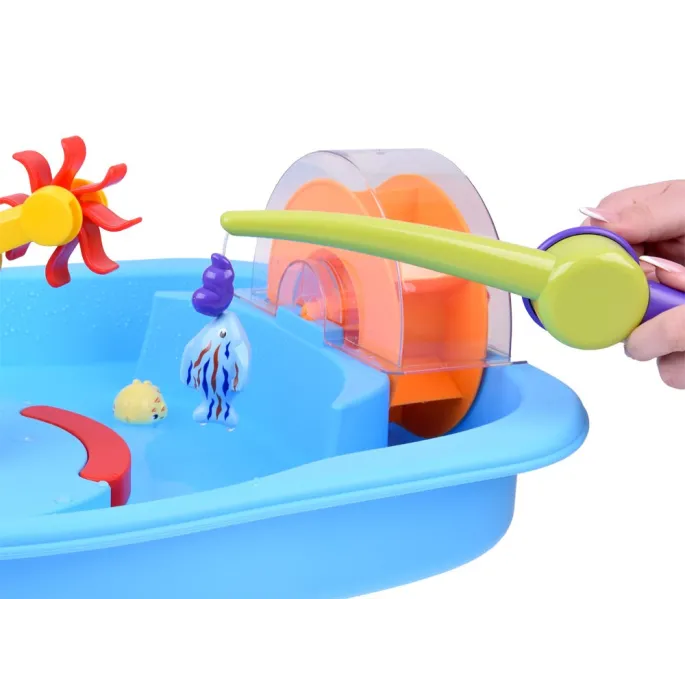 dziecko łowiące rybki plastikową wędką przy stoliku wodnym