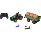 Figurka traktorzysty obok zielonego traktora z gumowymi oponami